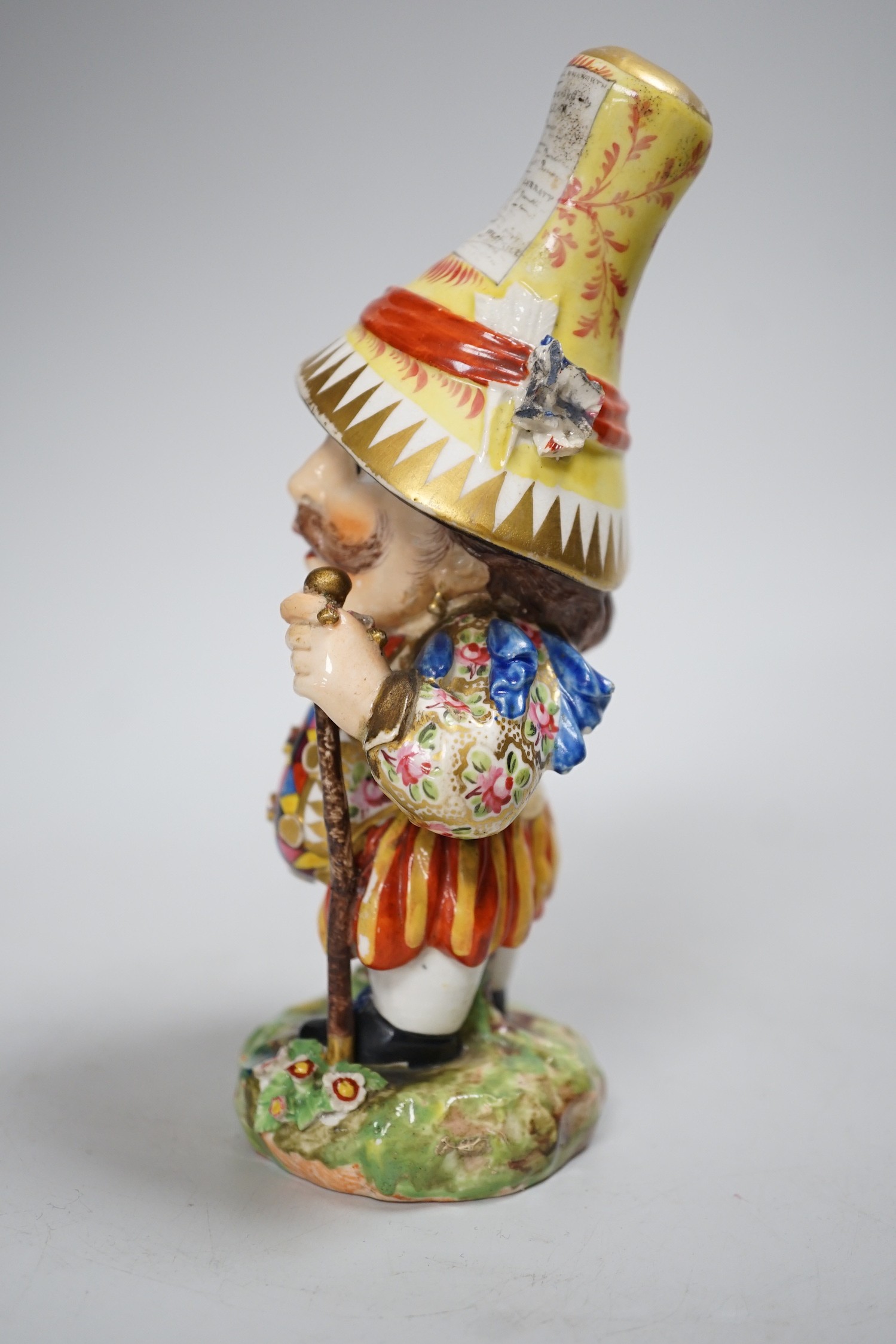 A Derby Mansion House Dwarf holding a walking stick, his hat with advertising, incised 227, c.1790-1800